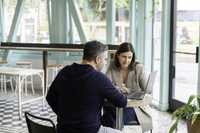 A man and woman collaborate at a table with a laptop, focusing on sales training and onboarding software solutions.